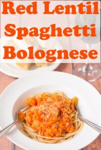 A bowl of red lentil spaghetti bolognese with a spoon and fork in. Pin title text overlay at top.