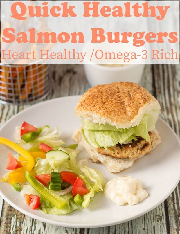 A quick healthy salmon burger served in a burger bun with a light side salad on a plate.