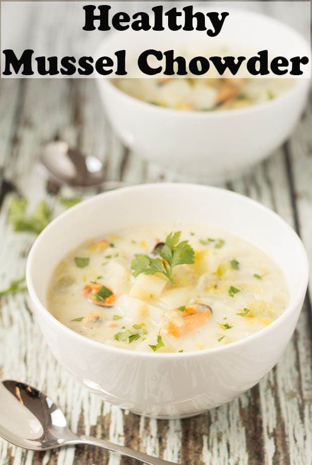 Two bowls of healthy mussel chowder garnished with fresh parsely one in front of the other with soup spoons to the side.