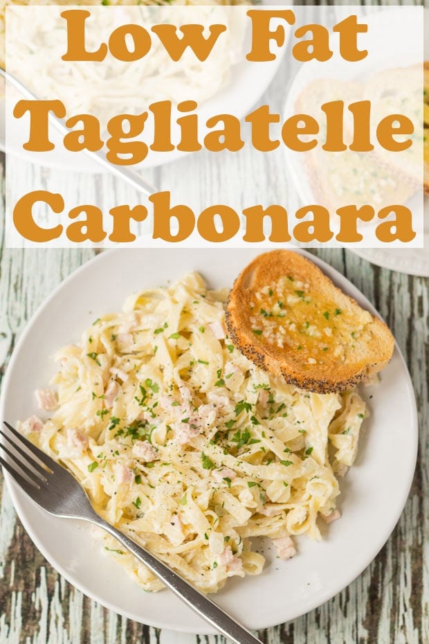 Overhead view of a plate of low fat tagliatelle carbonara with a fork and piece of garlic bread to the side.