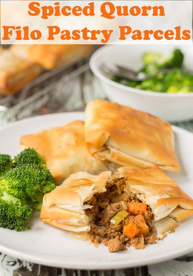 Three spiced quorn filo pastry parcels on a plate with one cut in half and the filling spilling out. Served with broccoli.