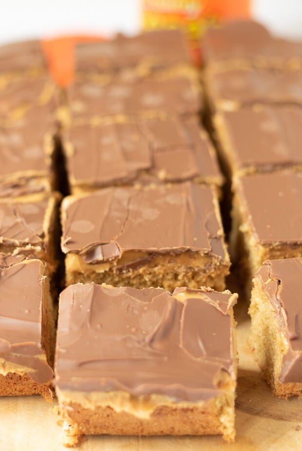Chocolate peanut butter tray bake sliced into squares on a chopping board.