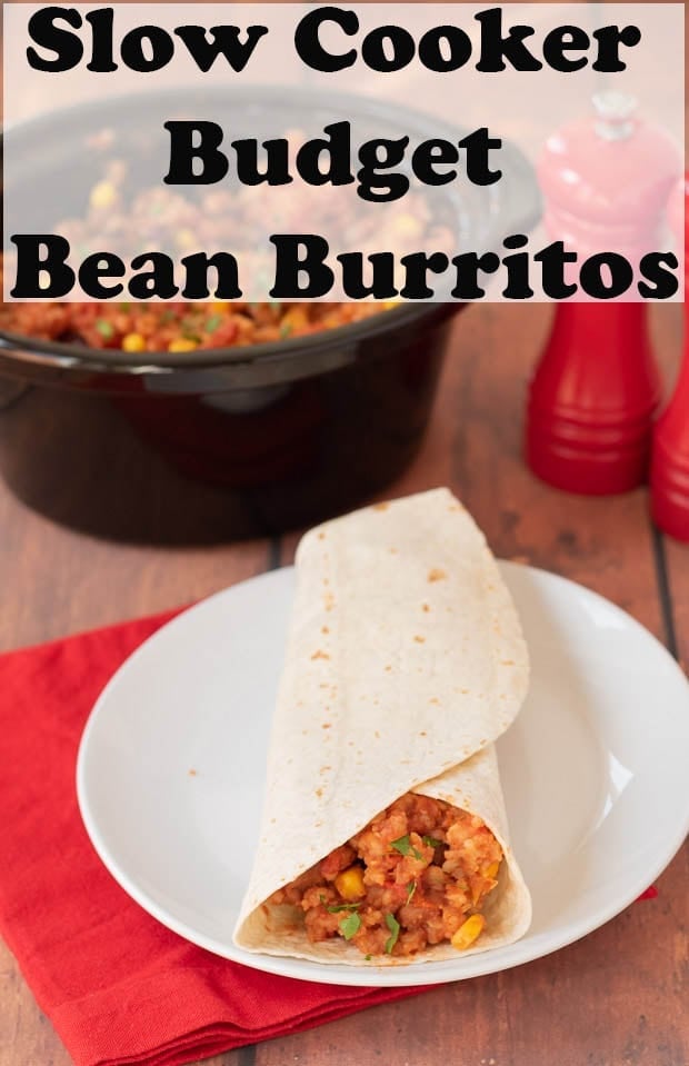A slow cooker budget bean burrito on a plate in front of the slow cooker containing the rest of the budget bean burritos.