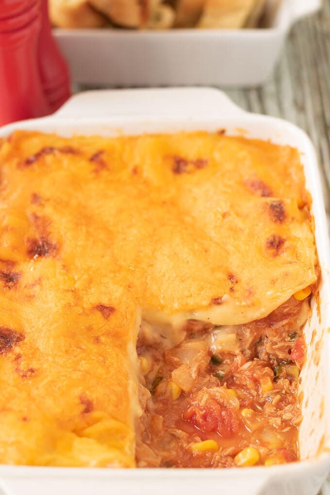 Close up of a casserole dish of tuna sweetcorn lasagne with a portion removed