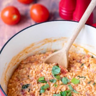Casserole pot of cooked tomato and basil risotto with spoon in ready to serve.