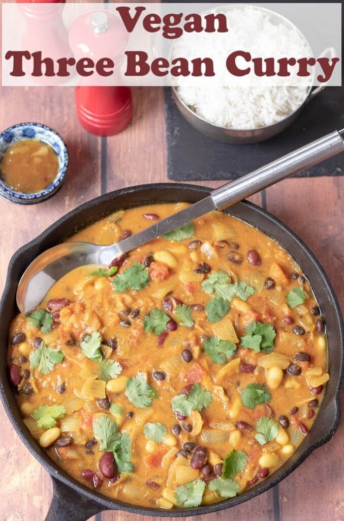 Birds eye view of a cooked pan of vegan three bean curry ready to serve and a balti dish of rice at the top.