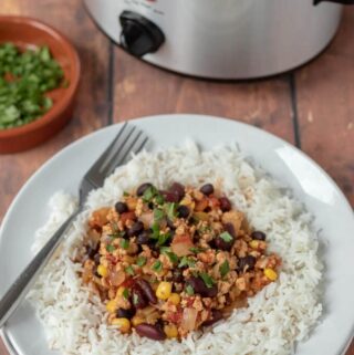 Healthy slow cooker turkey chilli served on rice and garnished with coriander.