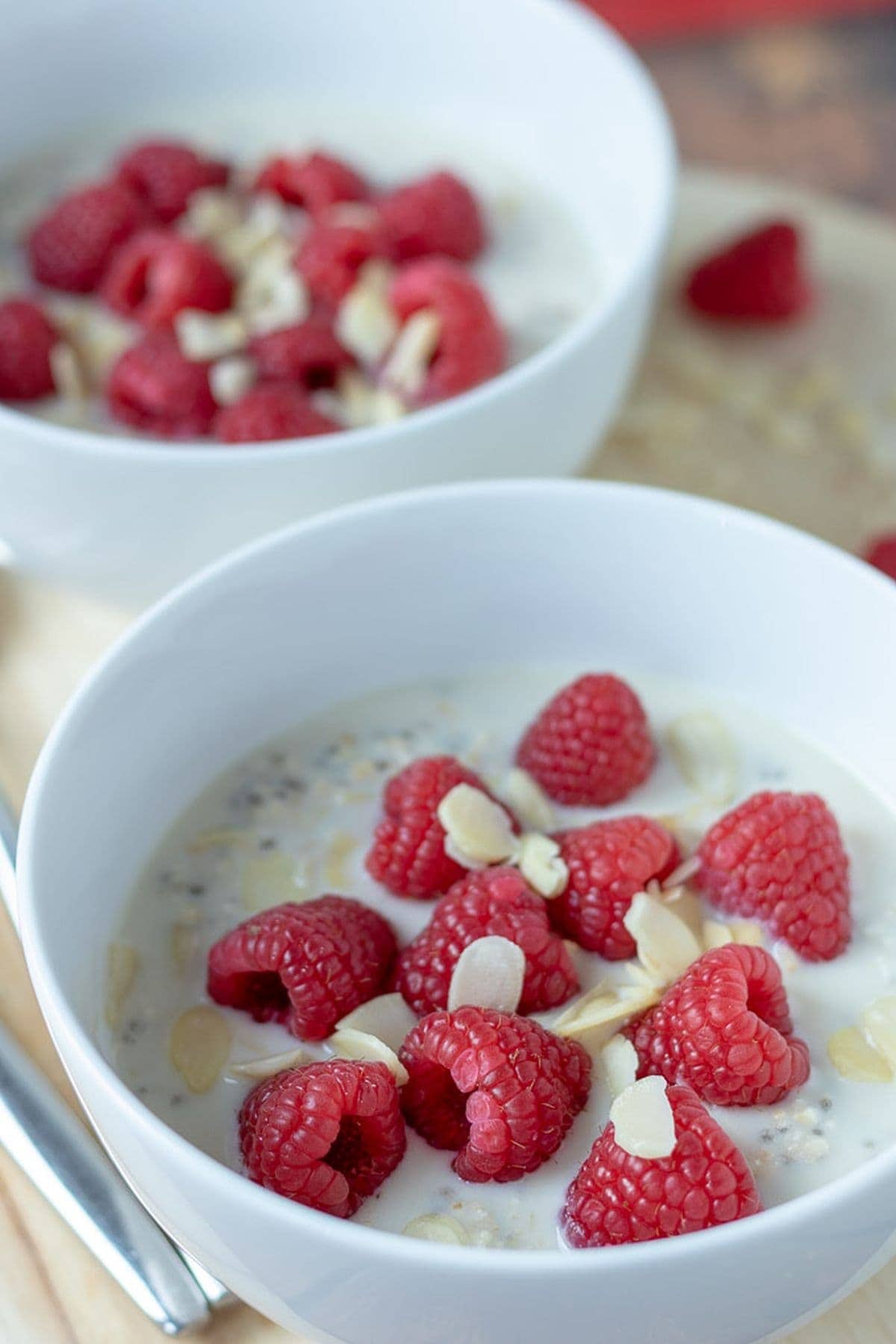 Raspberry overnight oats with almonds in two bowls one in front of the other served and ready to eat.