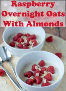 Raspberry overnight oats with almonds in a bowls one in front of the other served and ready to eat. Pin title text overlay at top.