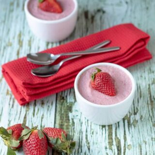 Two ramekins of strawberry vanilla pudding served with red napkins. Looks delicious and ready to eat!