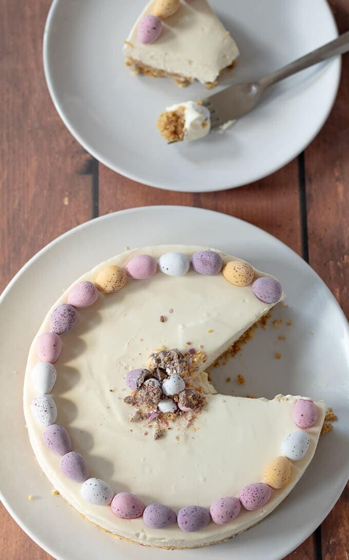 Birds eye view of this easy no-bake mini egg easter cheesecake with a slice taken out of it and that slice is on a plate just above ready to eat.