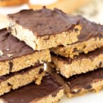 Chocolate peanut butter raisin flapjacks cut into bars and stacked on a serving plate.