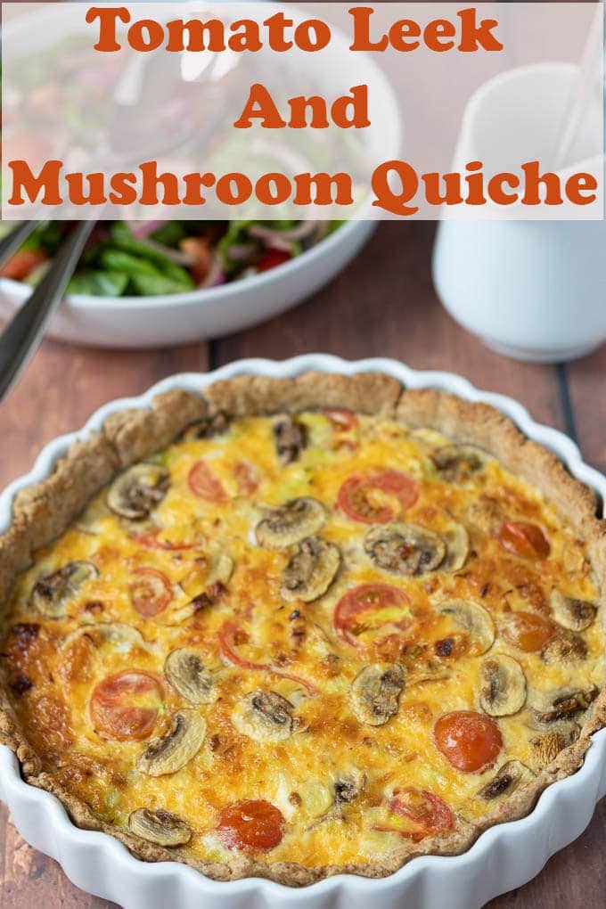 Tomato Leek and Mushroom Quiche straight out of the oven and ready to serve with a side salad and jug of salad dressing in the background.