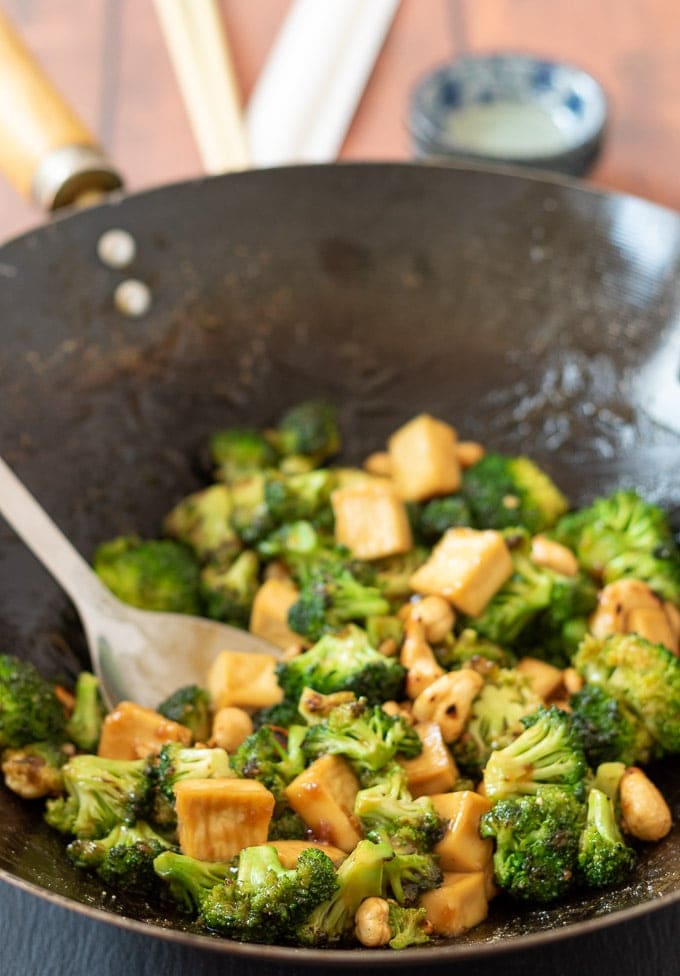 Cooked sticky peanut butter tofu stir-fry in a wok just finished cooking with a serving spoon ready to serve.