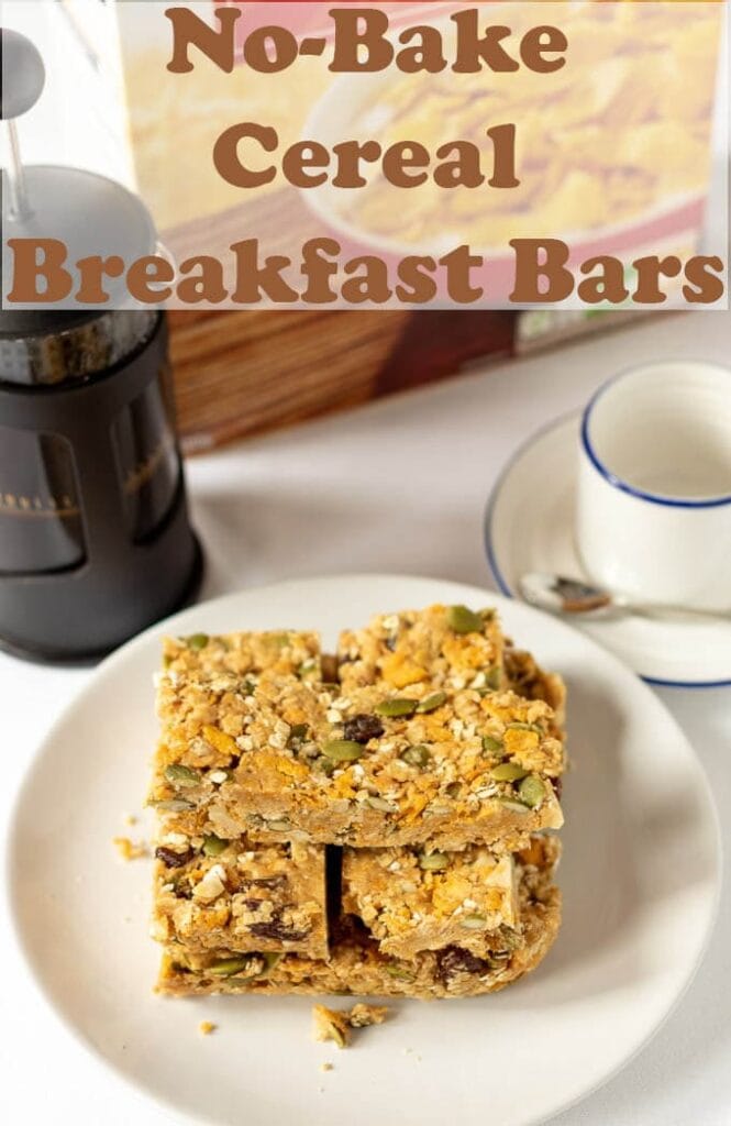 A plate with no-bake cereal breakfast bars stacked on it. A coffee cafetiere, coffee cup and box of cereal in the background.