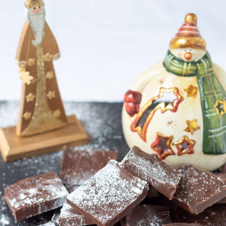 Easy healthy peppermint fudge squares on a slate dusted with icing sugar and a santa and snowman Christmas decoration in the background.