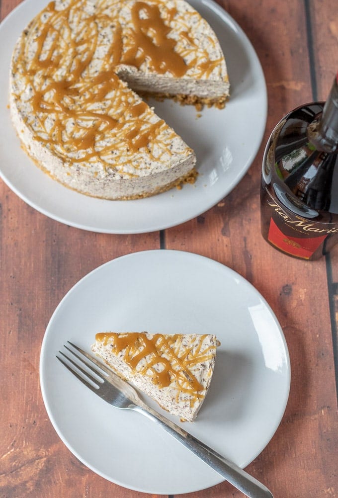 Birds eye view of no-bake Tia Maria cheesecake. One plate with the cheesecake on it and a slice taken out. The slice on another plate. A bottle of Tia Maria in between.