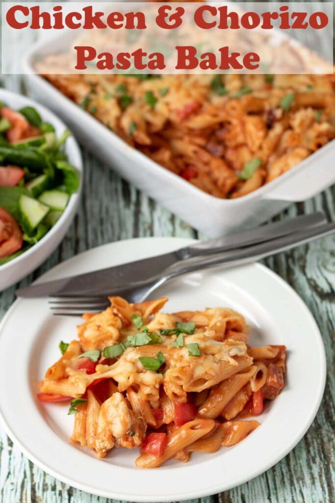 Chicken and Chorizo pasta bake served on a plate. A bowl of salad above and the rest of the bake in a casserole dish beside. Pin title text overlay at top.