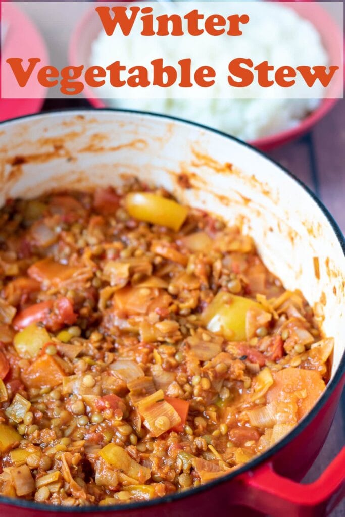 Birds eye view of a large casserole pot of cooked winter vegetable stew. Pin title text overlay at top.