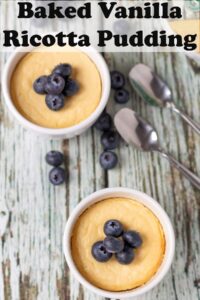 Birds eye view of two ramekins of baked vanilla ricotta pudding topped with blueberries and dessert spoons beside. Pin title text overlay at top.