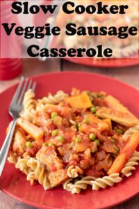 Two plates of vegetarian sausage casserole one in front of the other served on whole what fussili pasta. Pin title text overlay at top.