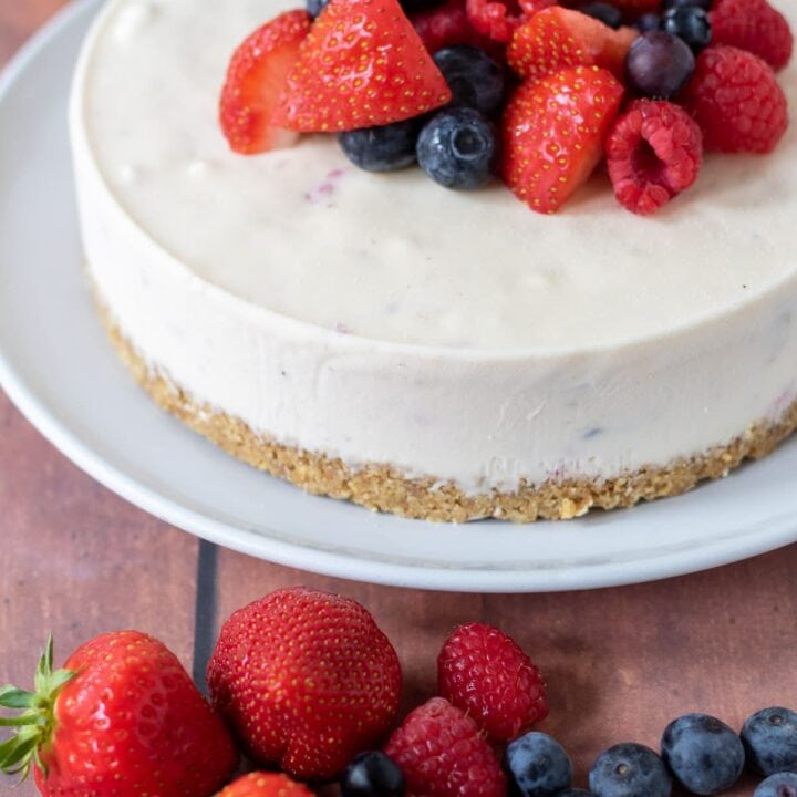 Summer fruits cheesecake in the background with a mixture of strawberries, raspberries and blueberries at the front.