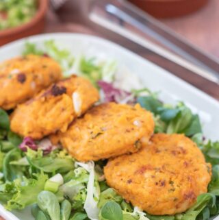 Four sweet potato cakes served on a bed of lettuce on a triangular serving plate,