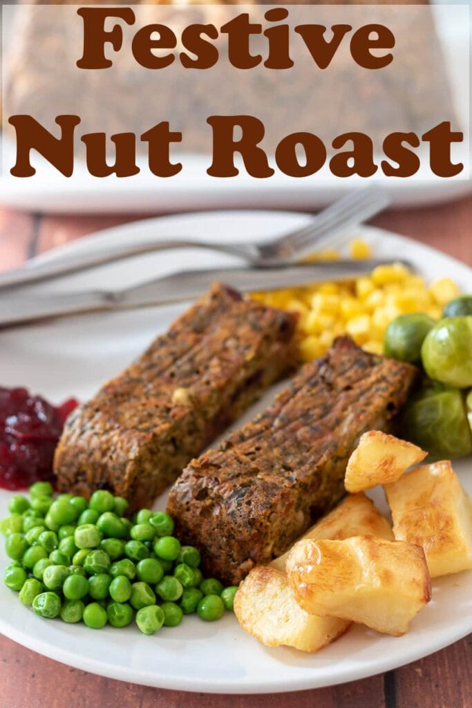 A plate with two festive nut roast slices on including peas, roast potatoes, sweetcorn and brussel sprouts. Cranberry sauce and a fork to the side. Pin title text overlay at top.