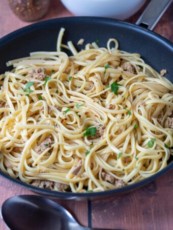 A pan of cooked tuna linguine with a serving spoon in front.