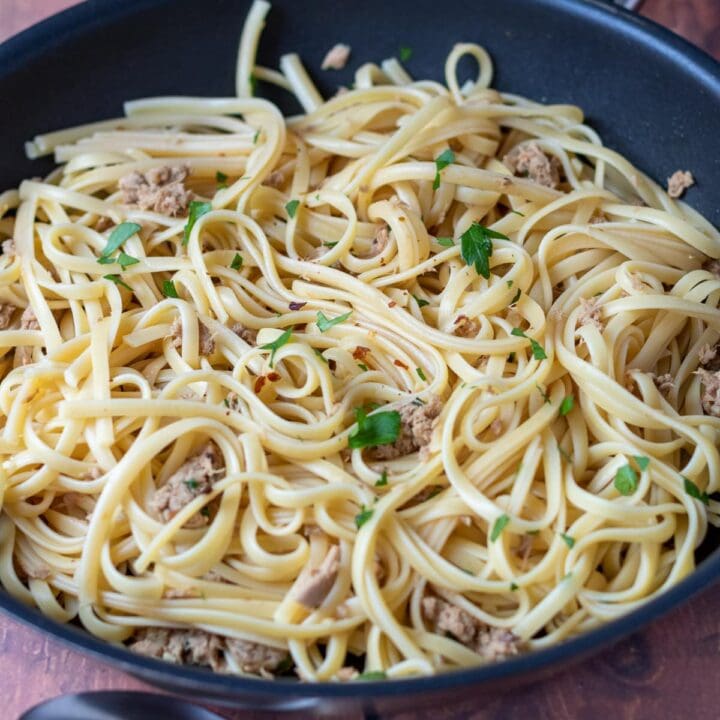 A pan of cooked tuna linguine with a serving spoon in front.