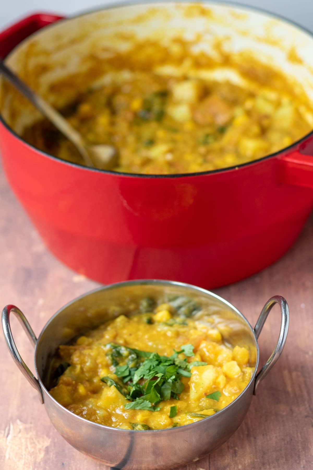 One pot vegetable dhal served in a balti dish with the rest in a casserole pot in the background.