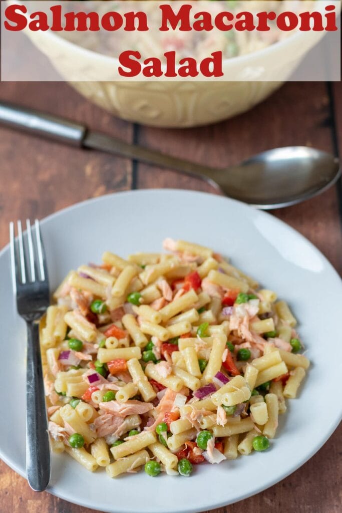 A plate of salmon macaroni salad with a fork to the left side. Serving spoon above plate. Pin title text overlay at top.