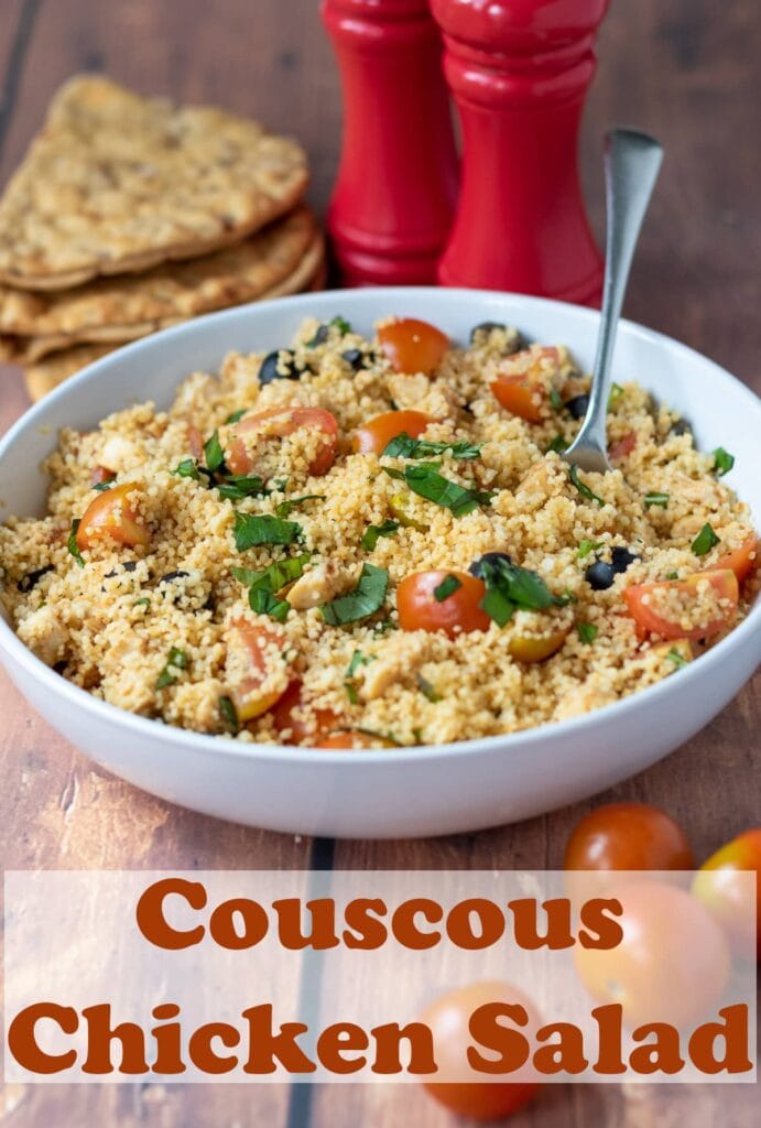 A bowl of couscous chicken salad with a serving spoon in. Pin title text overlay at bottom.