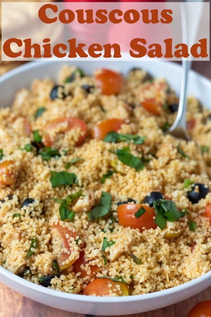 A bowl of couscous chicken salad with a serving spoon in. Pin title text overlay at top.