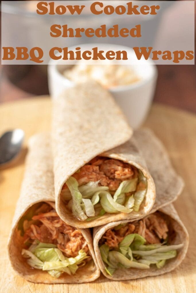 Three stacked slow cooker shredded BBQ chicken wraps on a chopping board with a ramekin of coleslaw in the background. Pin title text overlay at top.