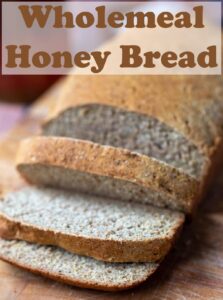 A loaf of wholemeal honey bread sliced on a bread board. Pin title text overlay at top.