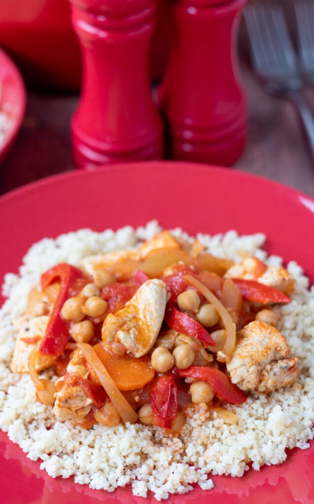 Chicken chickpea stew served on a bed of couscous with salt and pepper cellars in the background.