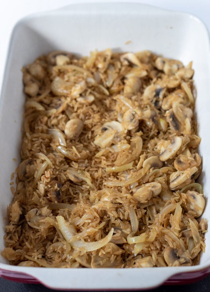 Brown rice, sauteed onion, garlic and mushrooms added to casserole dish. 