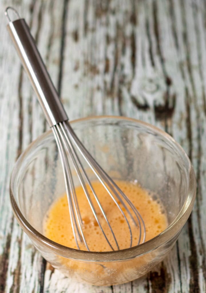 Eggs, sugar and vanilla whisked together in a small glass pyrex bowl.