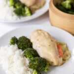Two plates of easy baked pesto mozzarella stuffed chicken served alongside white rice and steamed broccoli.