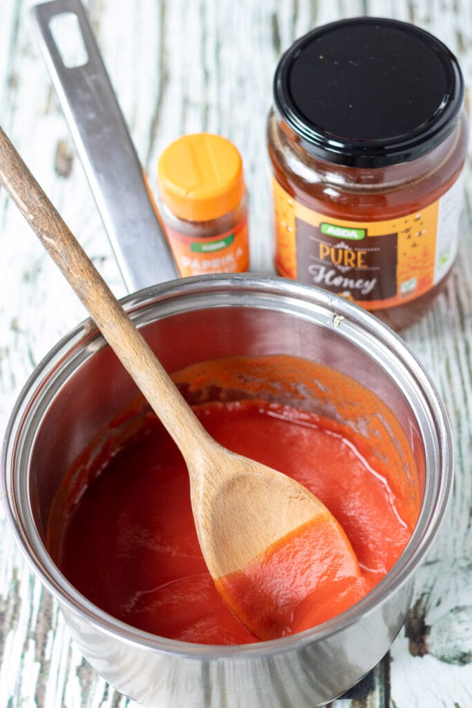 Honey and smoked paprika stirred into saucepan of tomato passata and tomato paste.