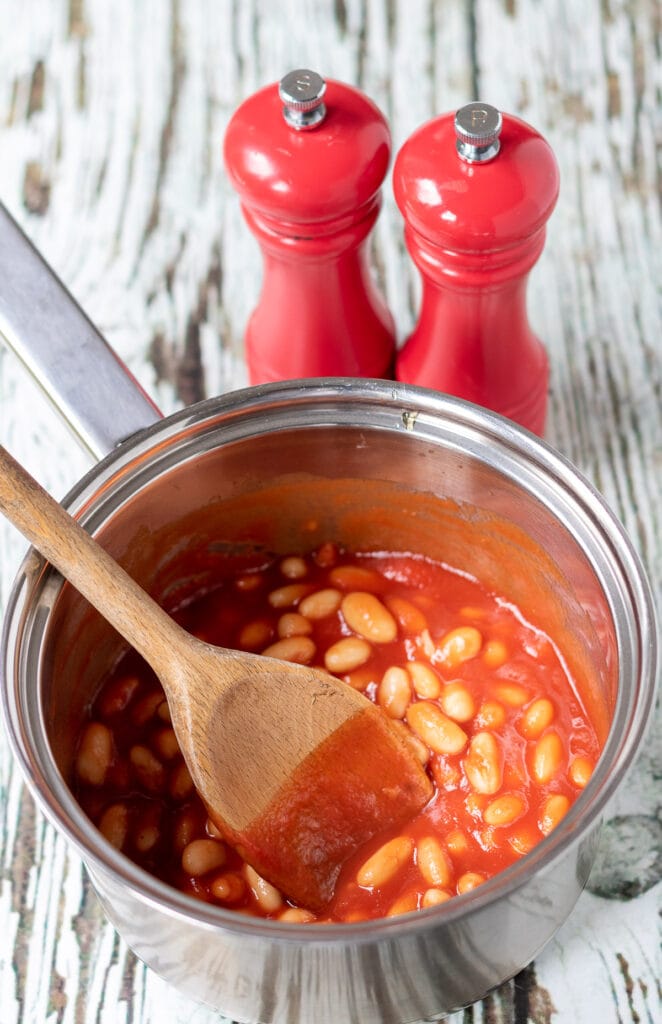 Home made British baked beans cooked in a saucepan with salt and pepper cellars above.
