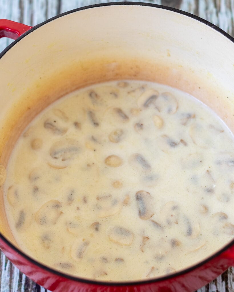 Stock, white wine and cream cheese added into casserole pot.