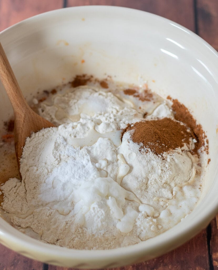 A large mixing bowl with dry ingredients flour, salt, cinnamon, baking powder, bicarbonate of soda and milk in.
