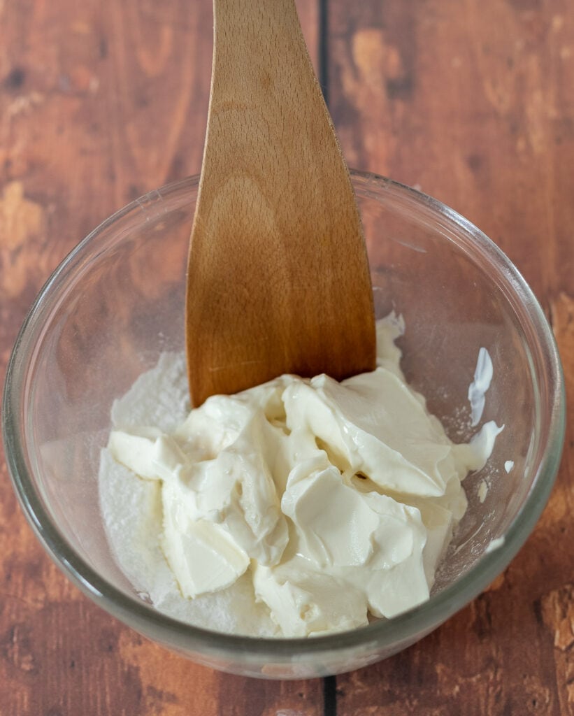 Icing sugar and cream cheese in a pyrex mixing bowl.