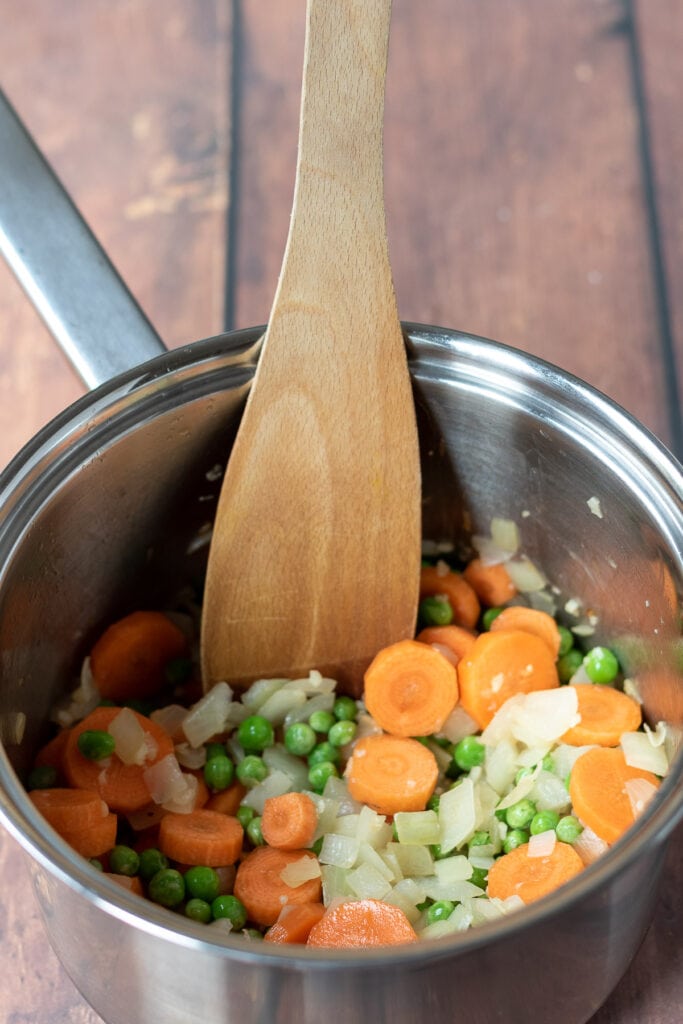 Carrots and frozen peas added to saucepan.
