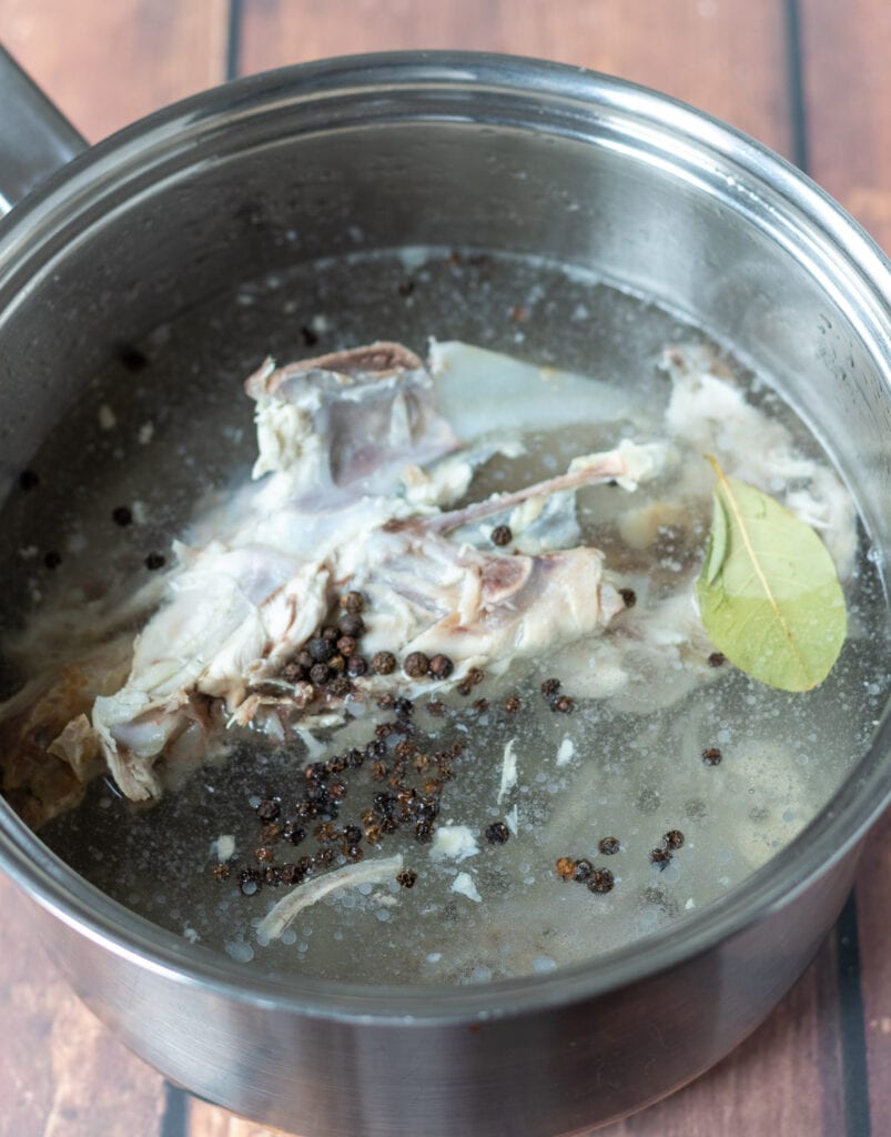 Chicken carcus placed into a large soup pot with black peppercorns and a bay leaf. Covered with cold water. 