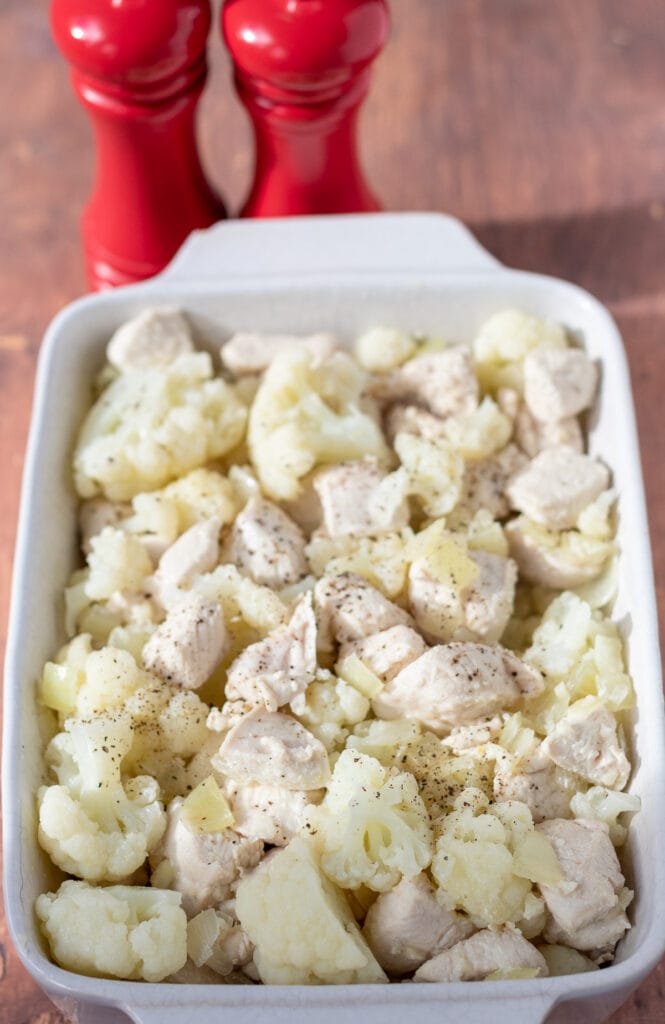 Cauliflower florets and chicken mixed together in an ovenproof dish.