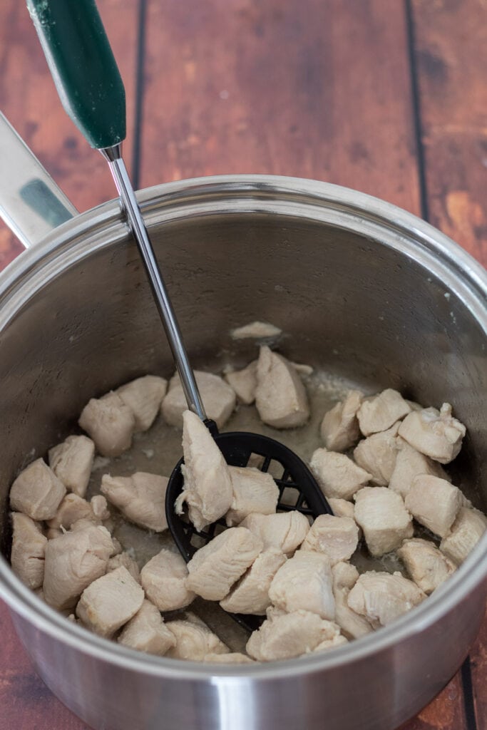 Cubes of chicken cooked in a large saucepan.