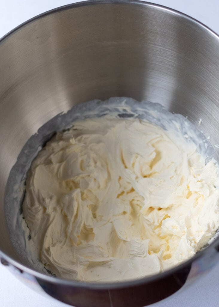 Double cream whisked to soft peaks in a stand mixer mixing bowl.